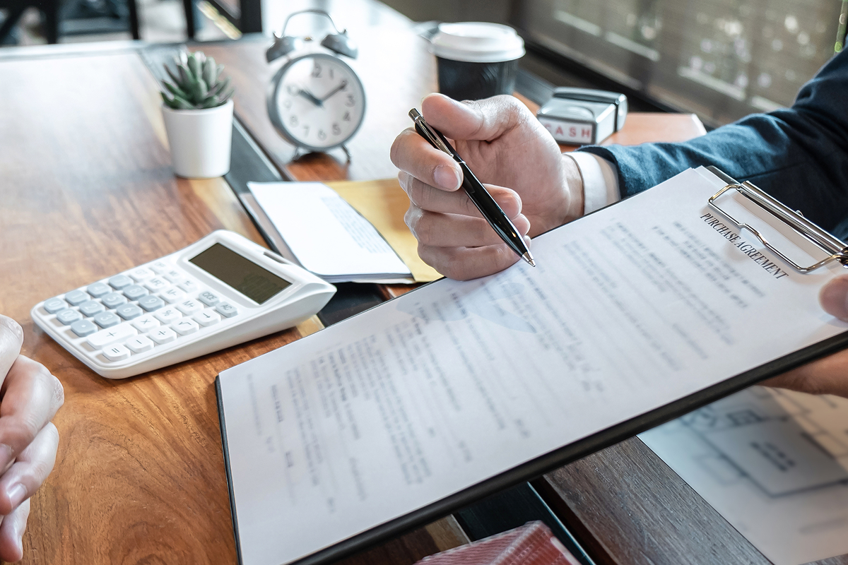 Male hands tilting a clipboard to a person, pointing to a line of text with a pen