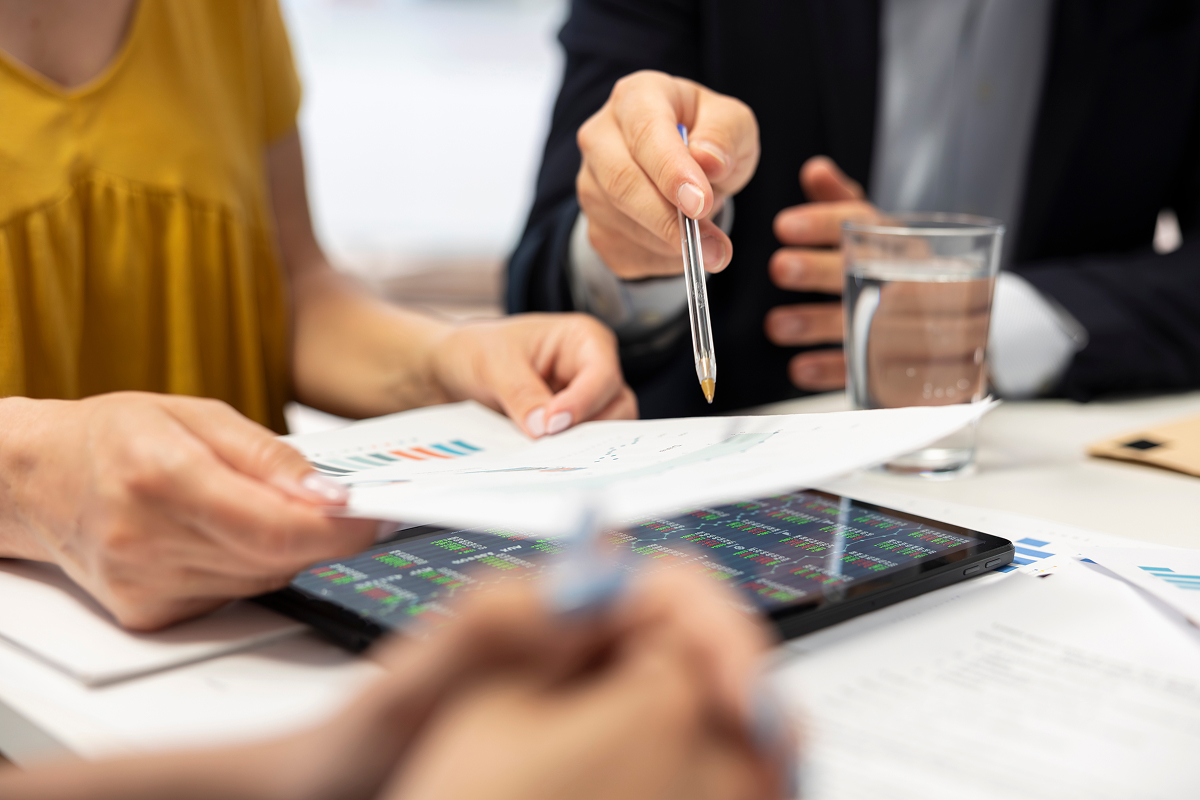 Three people going over data on paper and a tablet
