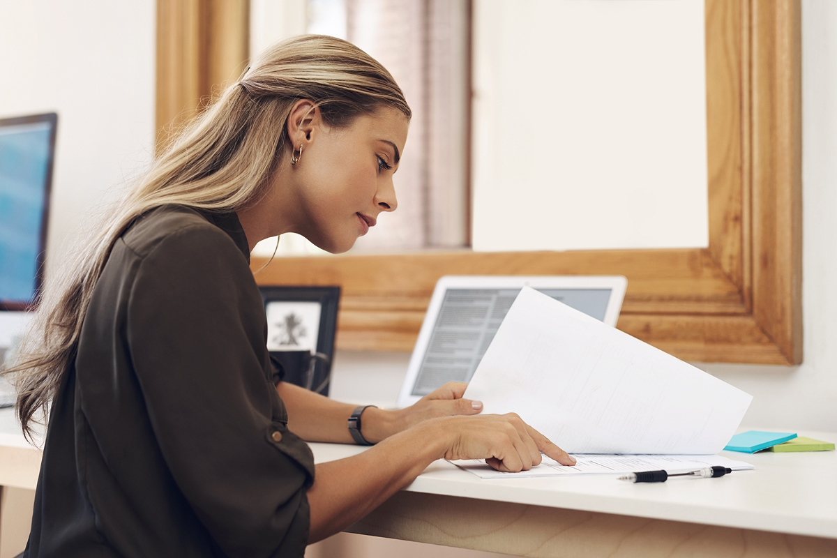 A woman examines paperwork at a desk